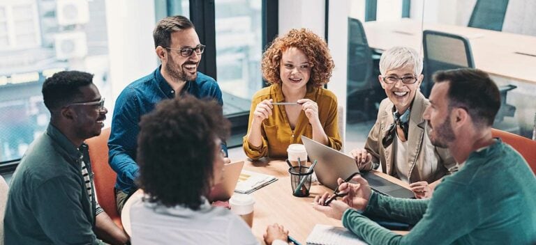A group of people sitting around a table in an office.